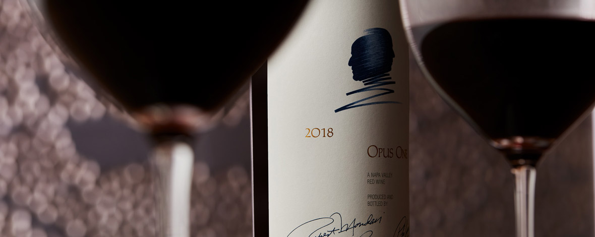 A macroshot of Opus One 2018 next to two wine glasses