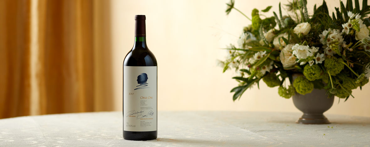 A magnum of Opus One 2017 next to green and white florals